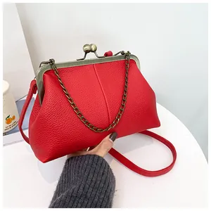 Detail of red litchi texture shell bag with antique bronze kiss lock and metal chain strap