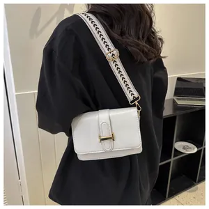 Détail du sac bandoulière en cuir blanc avec large bandoulière tissée noire et blanche