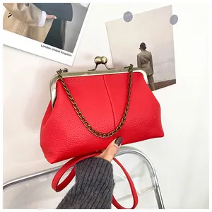 Detail of red lychee pattern leather shell bag with vintage metal clasp and chain