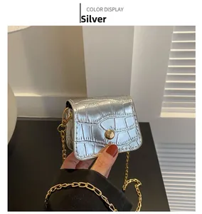 Detail of silver mini crossbody bag with crocodile pattern and golden chain strap