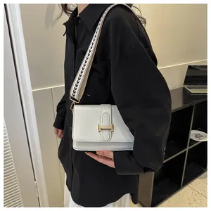 Détail d'un sac bandoulière en cuir blanc avec boucle en H et large sangle à motif