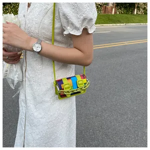 Detail of a mini crossbody bag featuring geometric color blocks and neon green chain link