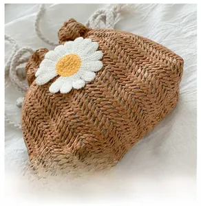 Close-up of woven straw texture and 3D daisy embroidery on a bucket bag bottom