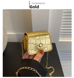 Detail of mini gold handbag featuring crocodile texture and metallic chain strap