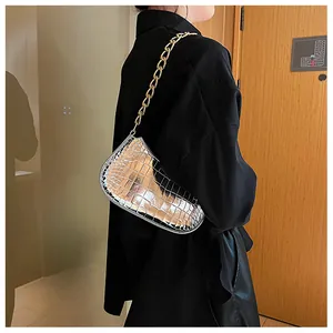 Detailed macro of silver faux-crocodile textured handbag with bold gold chain strap