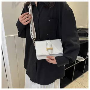 Détail du sac bandoulière blanc avec boucle dorée et large sangle aux motifs vagues