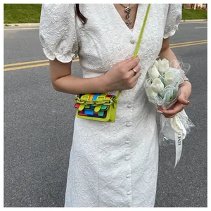 Close-up of mini rainbow patchwork crossbody bag with neon green plastic chain detail