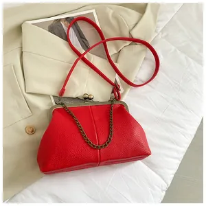 Detail of red lychee texture leather bag with metal clasp and decorative chain