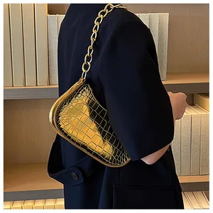 Detail of golden faux crocodile leather shoulder bag with glossy finish and chain