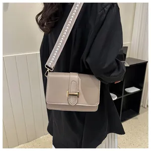 Détail d'un sac bandoulière carré avec sangle large à motifs et boucle métallique