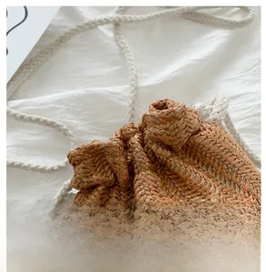 Detail of woven straw bucket bag featuring a white daisy applique and drawstring closure