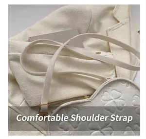 Detail of white heart crossbody bag featuring clover embossing and gold hardware