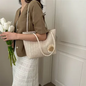 Detail of textured straw tote bag featuring a side flower and rope shoulder straps