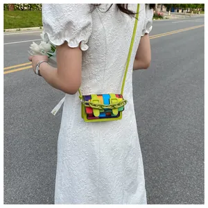 Detailed view of mini crossbody bag with neon green piping and geometric patchwork pattern