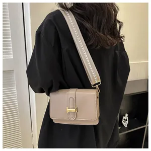 Détail du sac beige avec boucle en H dorée et bandoulière en toile tissée chic