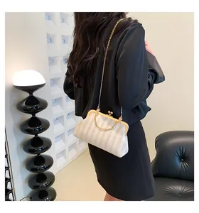 Détail du sac coquillage en paille tressée avec cadre en métal doré et bandoulière