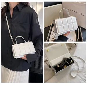 Détails du sac carré blanc matelassé montrant le rangement interne et le style porté