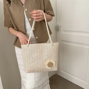 Detail shot of woven straw tote bag featuring decorative sunflower and rope handles