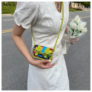 Detailed close-up of mini crossbody bag with colorful stripes and green chain on a model