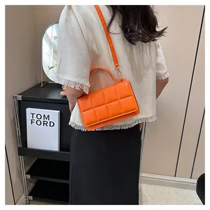 Gros plan sur un sac bandoulière orange vif matelassé avec rabat et bandoulière