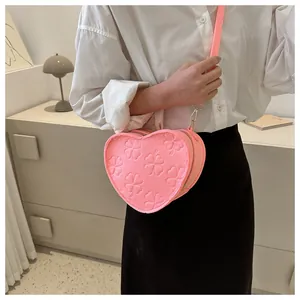 Detail of pink heart-shaped crossbody bag featuring embossed clover textures and zipper