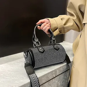 Detail of crystal-embellished cylinder bag with textured black and white woven strap