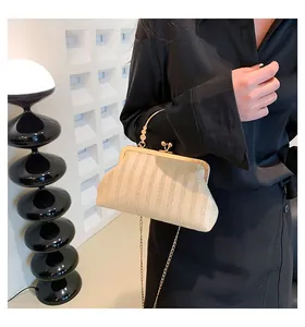 Détail du sac coquillage en paille tissée beige avec fermoir doré et chaîne