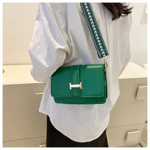 Détail du sac bandoulière en cuir vert avec boucle H dorée et large sangle tissée
