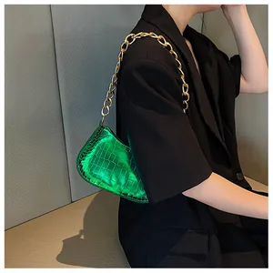 Detail of green faux leather underarm bag with crocodile texture and gold chain strap