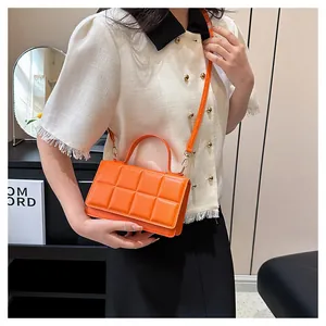 Détail du sac à main en cuir matelassé orange vif avec rabat magnétique et bandoulière