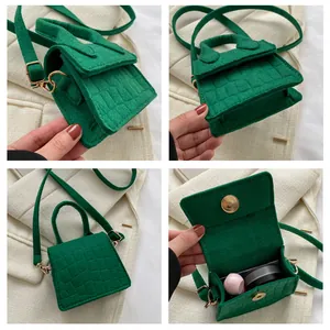 Detail van groene mini vilt crossbody tas met krokodillenprint en gouden hardware