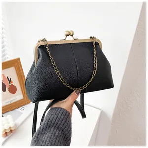 Close-up of black litchi pattern leather shell bag with vintage bronze metal clasp and chain
