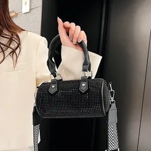 Detailed macro view of black rhinestone cylinder bag with V-pattern wide woven shoulder strap