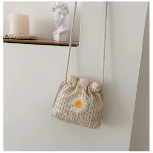 Straw drawstring bucket bag with daisy embroidery and thin woven shoulder strap