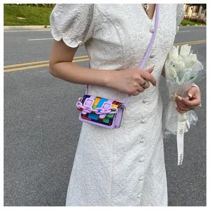 Mini rainbow checkered crossbody bag with purple chain detail on white lace dress