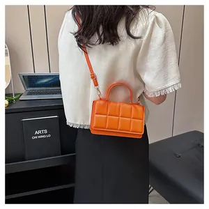 Sac à bandoulière matelassé orange chic avec boucle dorée porté par un mannequin