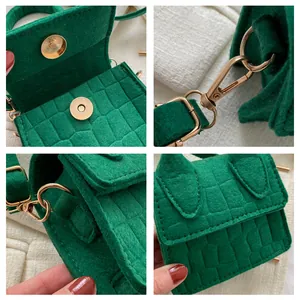 Detailoverzicht van mini groene vilt crossbody tas met krokodillenprint en gouden magneetsluiting