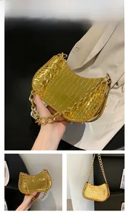 Detail of gold crescent shoulder bag with crocodile texture and chunky metal chain