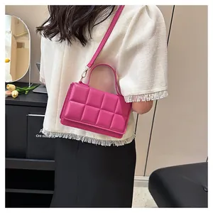 Gros plan d'un sac bandoulière matelassé rose rouge avec ferrures dorées et cuir
