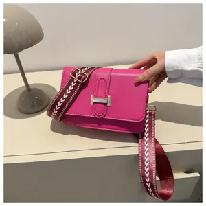 Détail du sac bandoulière rose fuchsia avec fermoir H doré et large sangle à motifs