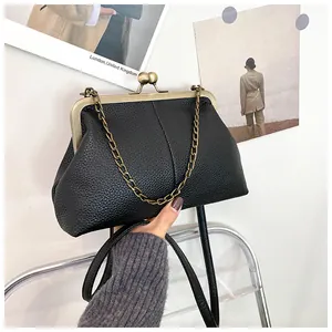 Detail of black shell bag with lychee texture and bronze metal clasp with chain