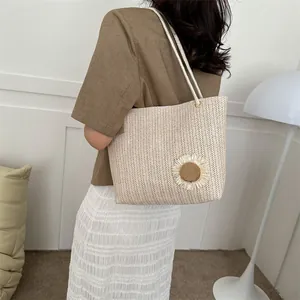 Detail of straw tote bag featuring decorative woven sunflowers and white rope handles