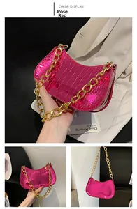 Detail of hot pink crocodile pattern shoulder bag with a bold gold chain strap