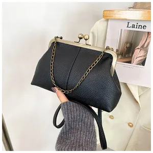 Close-up of litchi texture leather shell bag with gold clasp and pearl chain handle