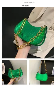 Detail of green crocodile texture shoulder bag with decorative gold chain strap