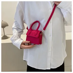 Mini fuchsia crossbodytas met krokodillenreliëf gedragen door een model in een strak decor