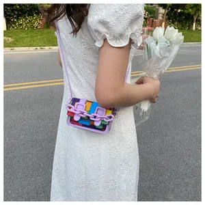 Detail of rainbow patchwork mini crossbody bag with purple chain and lace dress