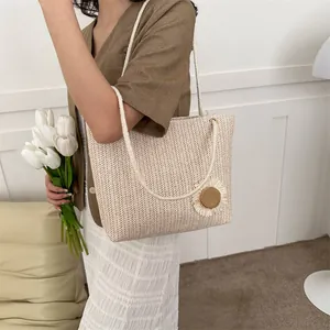 Detail of a beige woven tote bag with a white rope strap and large floral 3D ornament