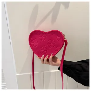 Detail of rose red heart-shaped bag with embossed clover pattern and gold metal hardware