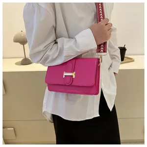 Détail du sac bandoulière fuchsia avec boucle en H dorée et large sangle tissée